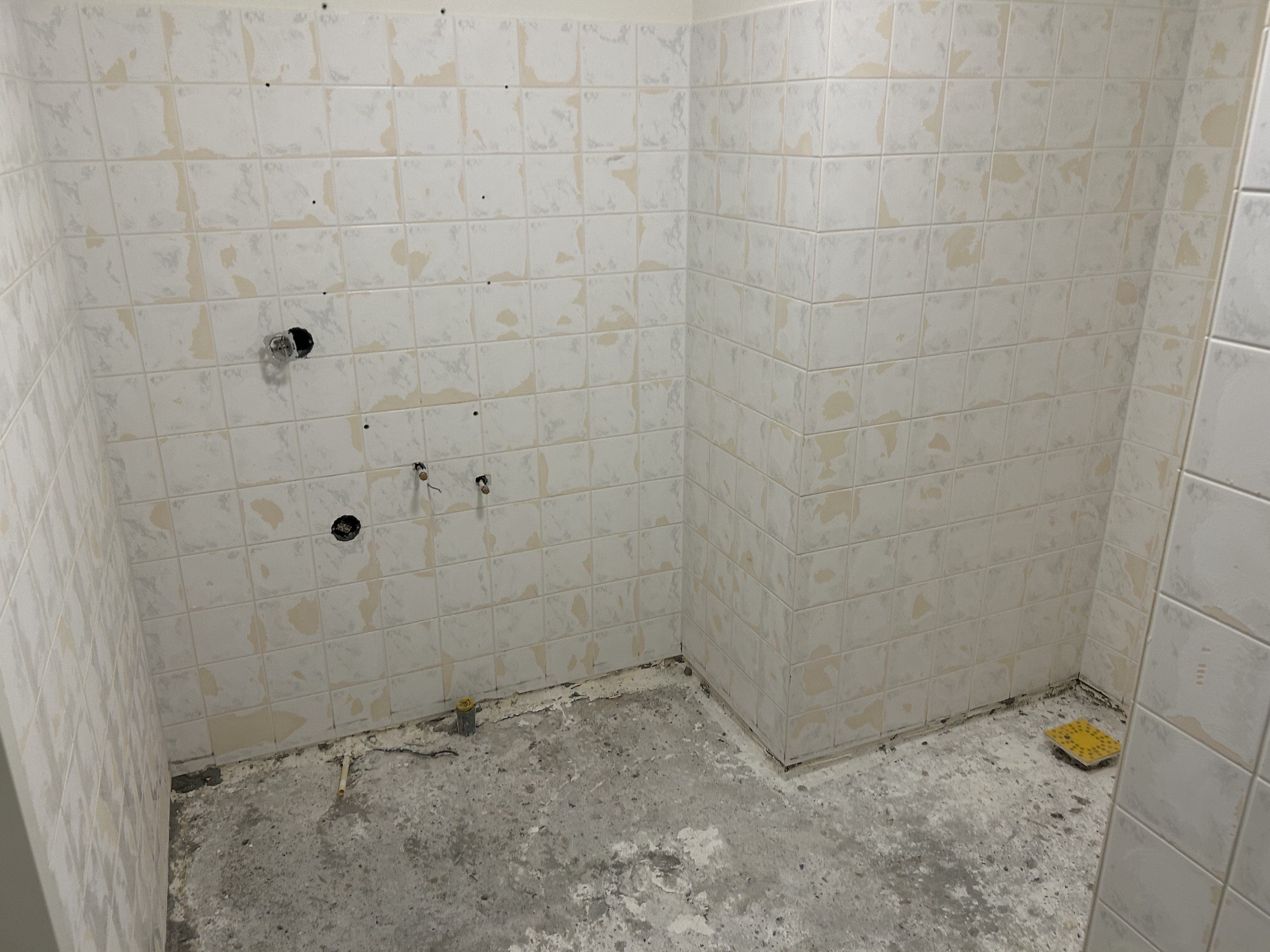 Badkamer waarvan de wandtegels zijn opgeruwd en de vloer is verwijderd.