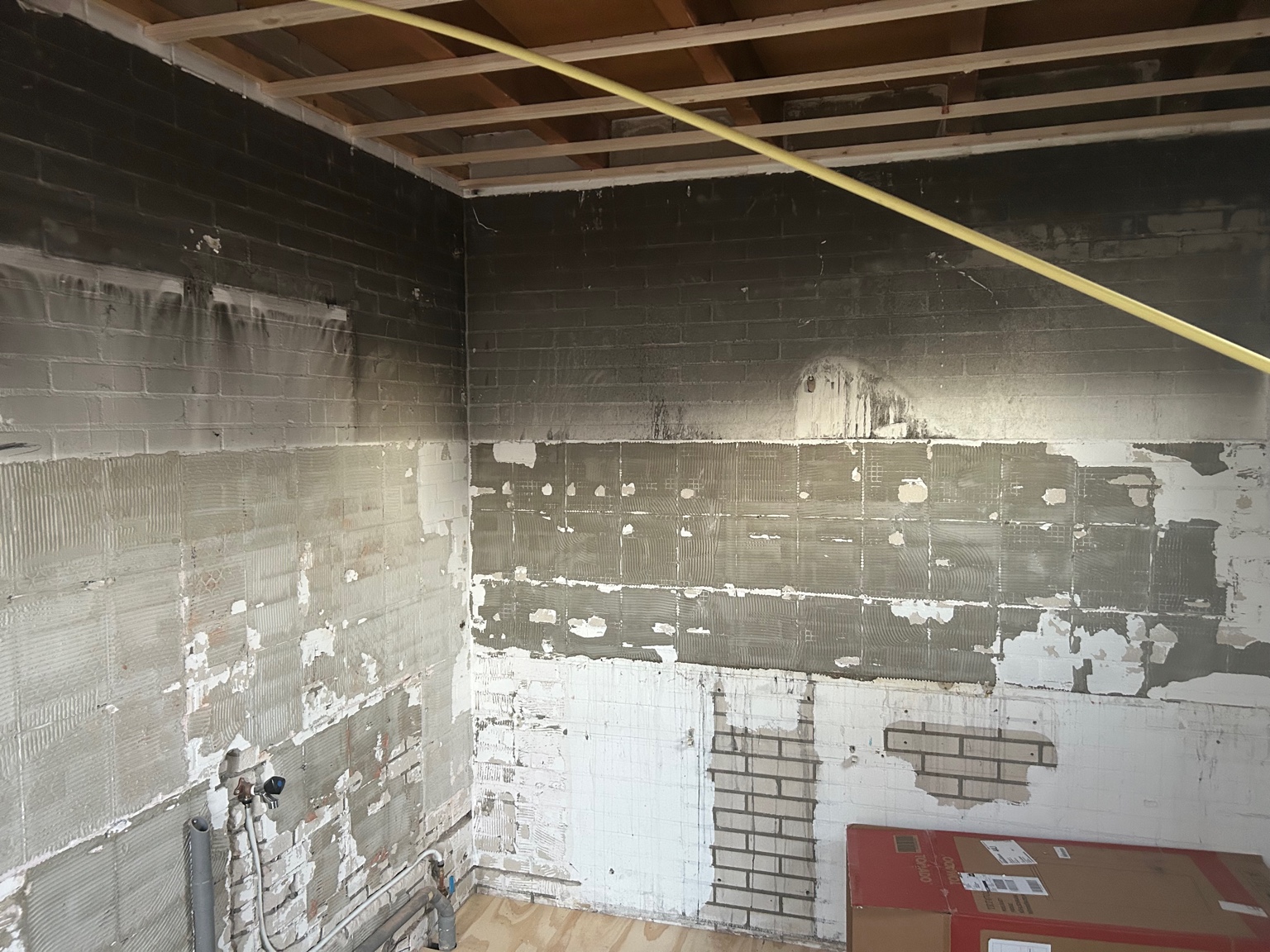 Keukenmuur na het vrezen van roet en verwijderen van tegels na brandschade.